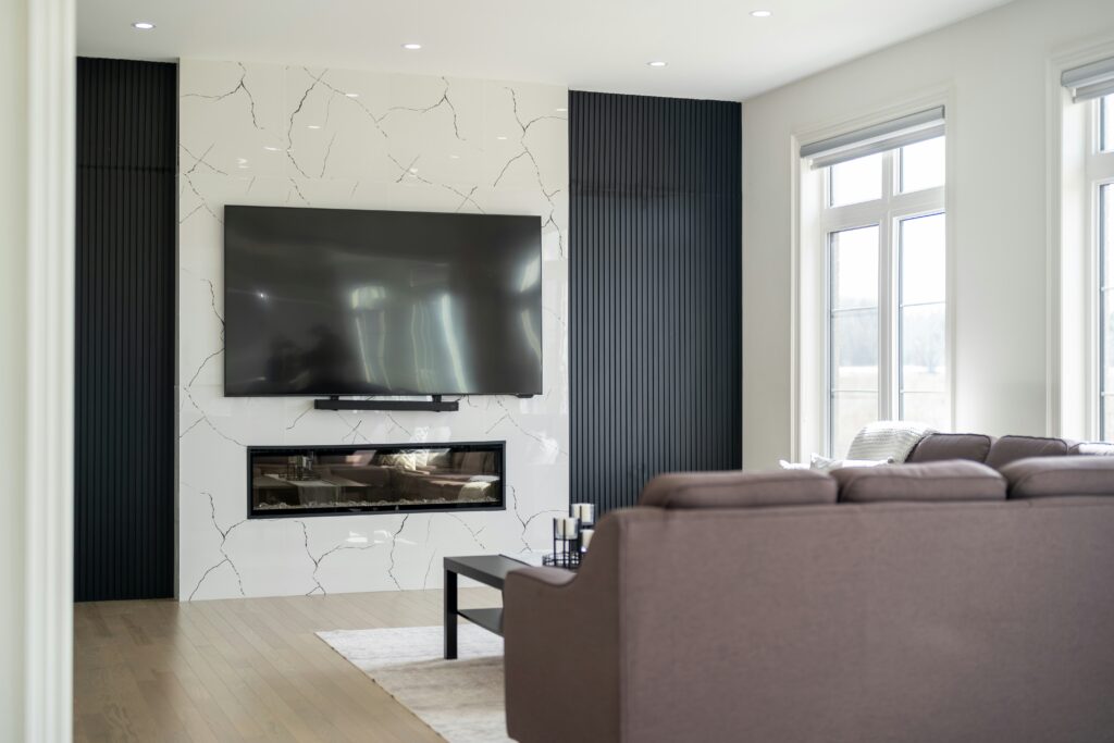 A large flat-screen television mounted on the wall above a fireplace in a bright modern living room