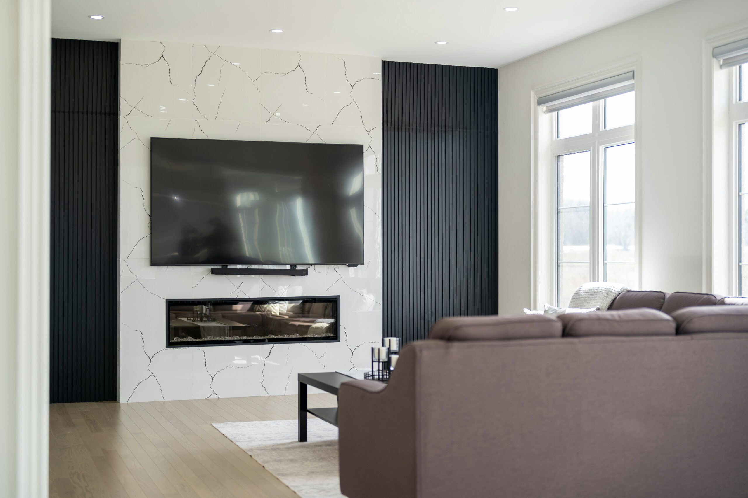 A large flat-screen television mounted on the wall above a fireplace in a bright modern living room
