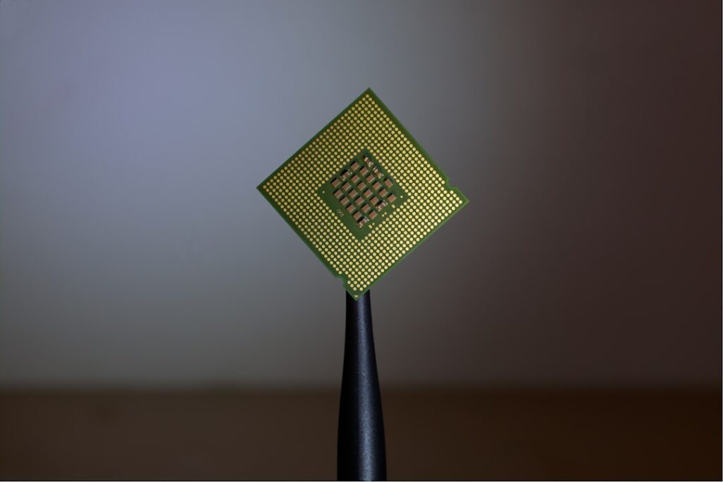 Close-up macro of a computer memory chip and its gold circuit contacts on a green circuit board, representing Samsung AI memory hardware.