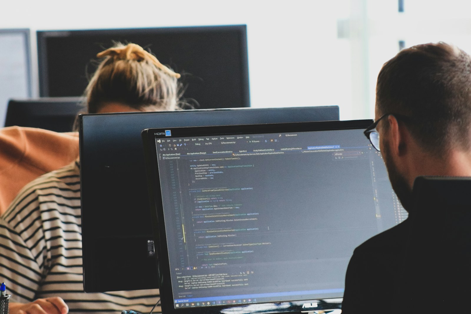 Two software developers reviewing code together at computer monitors